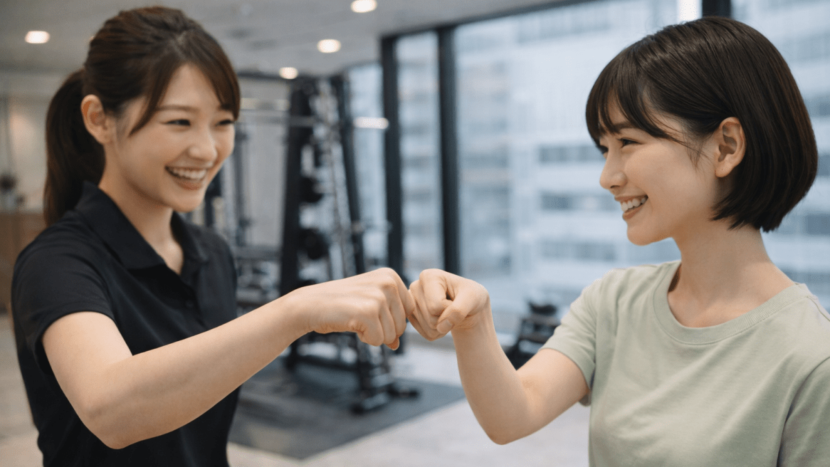 パーソナルジムでトレーニング成功を喜び女性トレーナーと会員がフィストバンプ